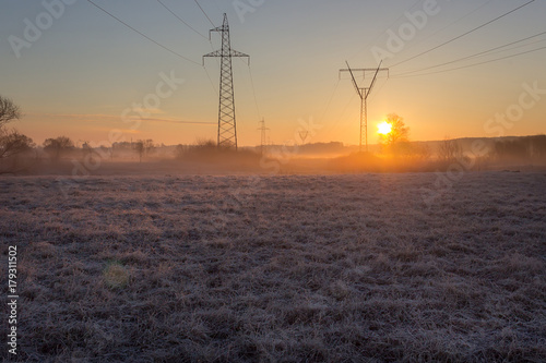 High voltage line supports in fog at frosty spring sunrise morning © Kakabadze