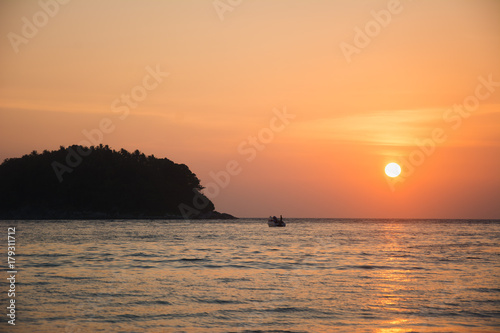 Small island and boat at sunset