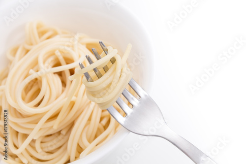 Plain cooked spaghetti pasta in white bowl and on fork  on white background.