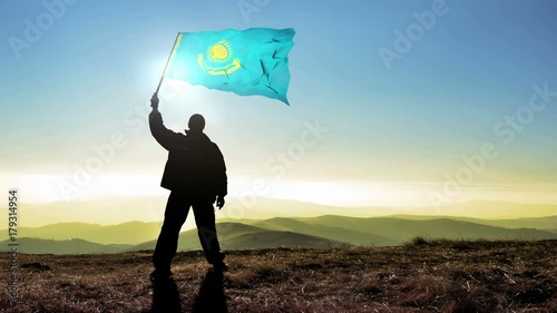 Successful silhouette man winner waving Kazakhstan flag on top of the mountain peak, Cinemagraph LOOP background photo