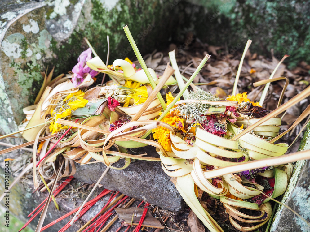 Stacks of old dried canang sari offerings at the base of a stone statue, Amed, Bali, Indonesia Stacks of old dried canang sari offerings at the base of a stone statue, Amed, Bali, Indonesia