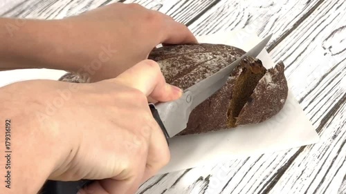 Black sweet bread girl hand cutting into slices with dried fruits and nuts covered with powdered sugar chef cuts large piece traditional cake over manicure white background wooden board plastick