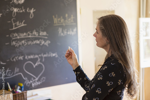 Pensive teacher holding chalk near blackboard