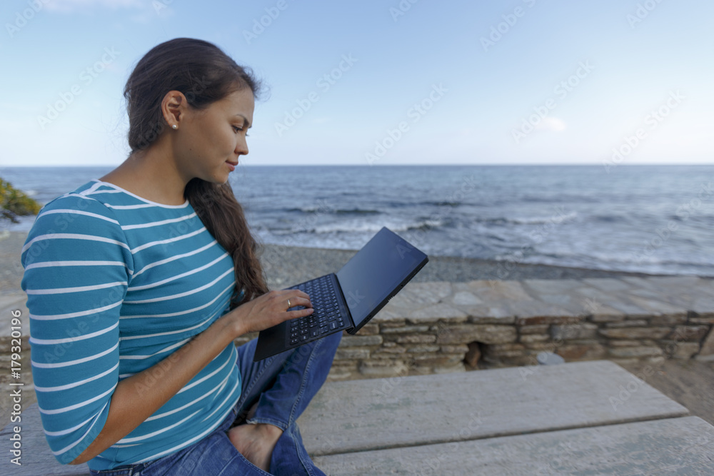 An Asian woman is working with laptop on a beach