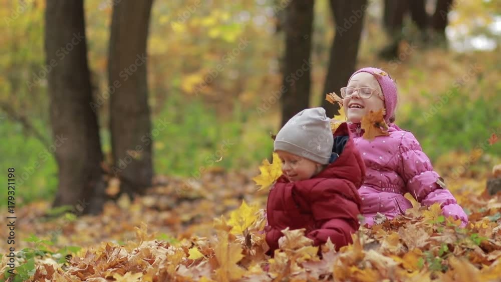 Cheerful children playing in leaves pile in autumn Cheerful children playing in leaves pile in autumn