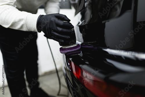 Car detailing - Worker with orbital polisher in auto repair shop. 