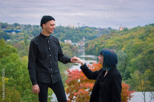 Gothic couple love story. Man and blue hair girl at black clothes at green river background
