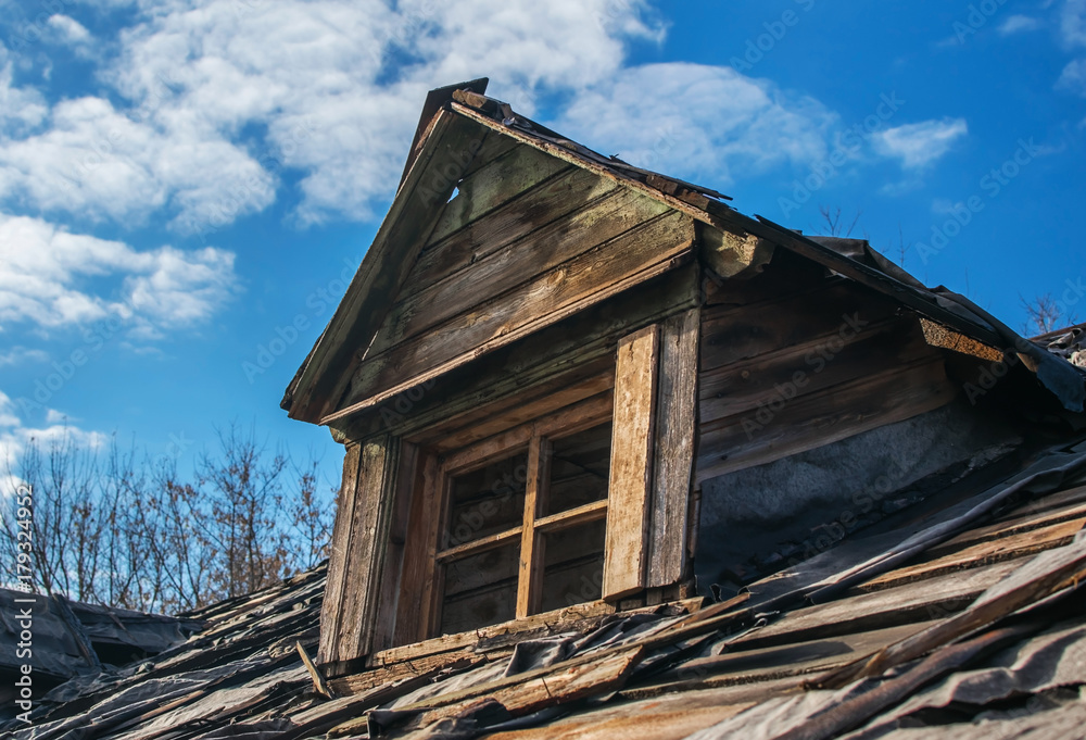 An old abandoned ruined wooden building. A roof of a destroyed house. Old attic with window. A decrepit roof An old abandoned ruined wooden building. A roof of a destroyed house. Old attic with window. A decrepit roof