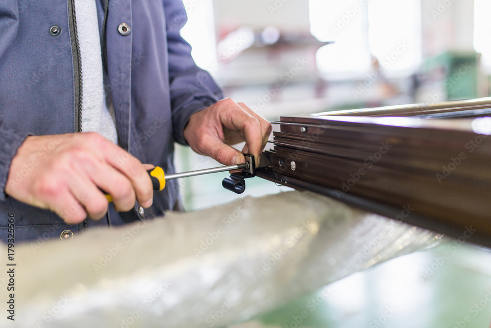 Obraz premium Factory for aluminum and PVC windows and doors production. Manual worker assembling PVC doors and windows. 