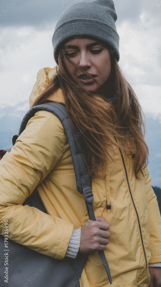 Hipster young girl with backpack hiking in mountains. Tourist traveler walking on top of the mountain Hipster young girl with backpack hiking in mountains. Tourist traveler walking on top of the mountain