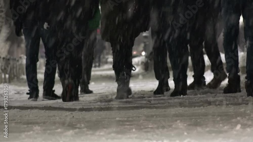 People feet walking on walkway during snow blizzard, winter town scape in a snowfall photo