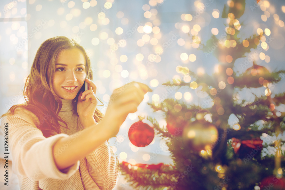 woman with smartphone decorating christmas tree woman with smartphone decorating christmas tree