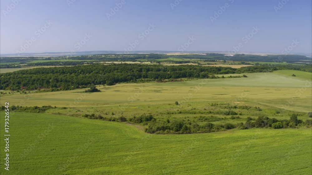 Wide aerial shot of green field under blue sky / Balvan, Bulgaria Wide aerial shot of green field under blue sky / Balvan, Bulgaria