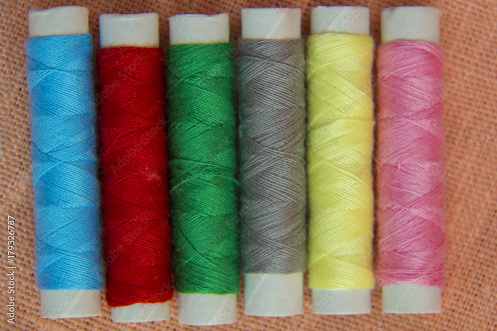 Sewing threads multicolored on linen background closeup.