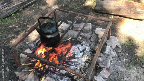Top view: Boiling kettle smoke fire log steam Camping Burning Fire hiking camp woods nature wood trip burning under authentic summer kitchen camping scene backpack axe tea pot boiling open fire