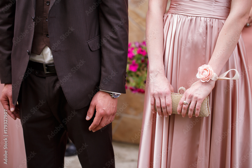 man in an elegant suit and an expensive watch is at the woman in pink long dress