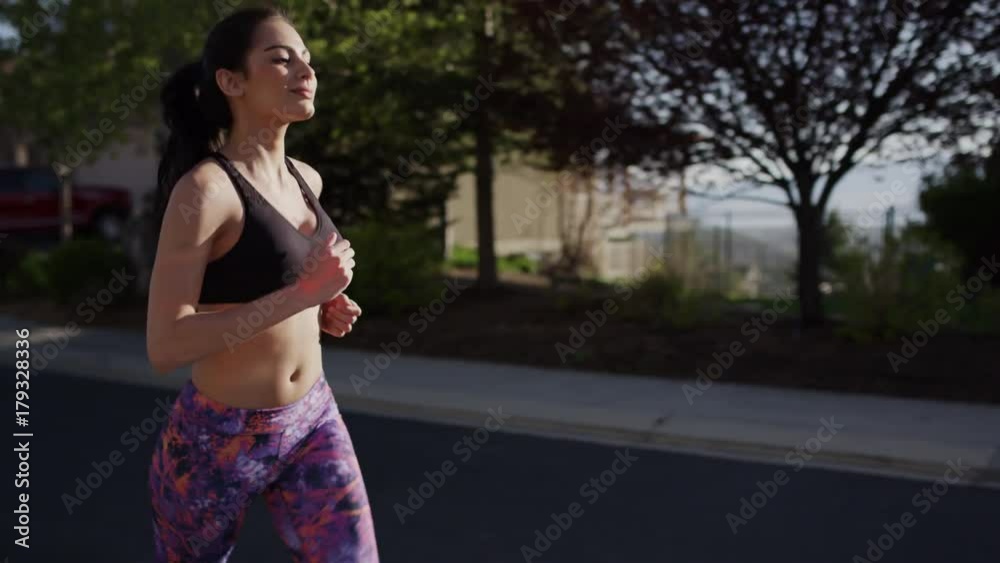 Medium tracking shot of woman running in suburban road / Cedar Hills, Utah, United States Medium tracking shot of woman running in suburban road / Cedar Hills, Utah, United States