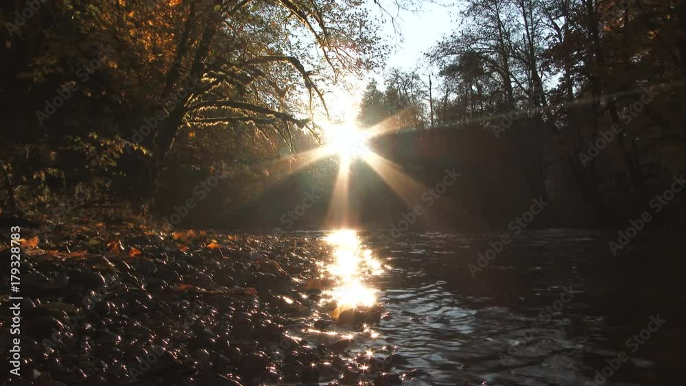 A couple walk along the river's shore during sunset in the fall, low angle with model releases. A couple walk along the river's shore during sunset in the fall, low angle with model releases.
