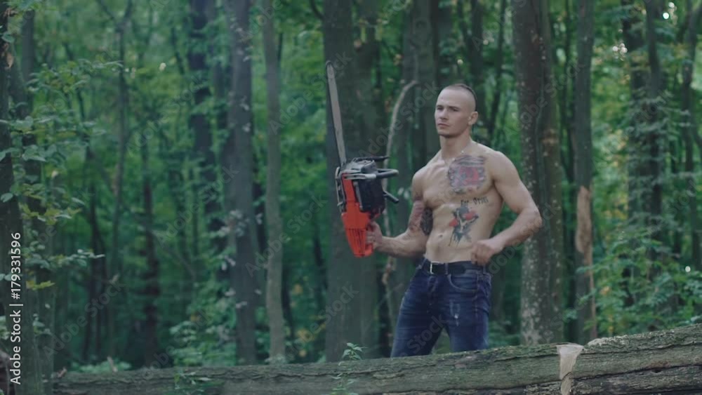 The strong woodcuter sawing the tree with chainsaw. Slowly The strong woodcuter sawing the tree with chainsaw. Slowly