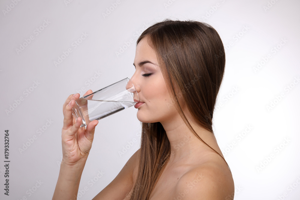 Hübsche junge Frau mit nackten Schultern trinkt ein Glas Wasser Hübsche junge Frau mit nackten Schultern trinkt ein Glas Wasser