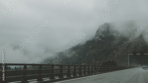 POV car driving on a mountain highway, clouds flying low