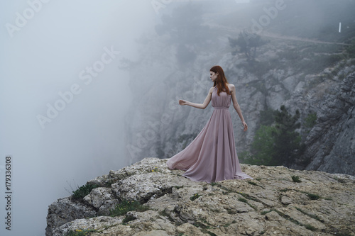 Woman wearing dress standing on rock in fog