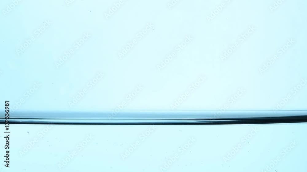 Shaking pure clear cold water surface level in transparent glass jar or teapot, close up, low angle side view, slow motion