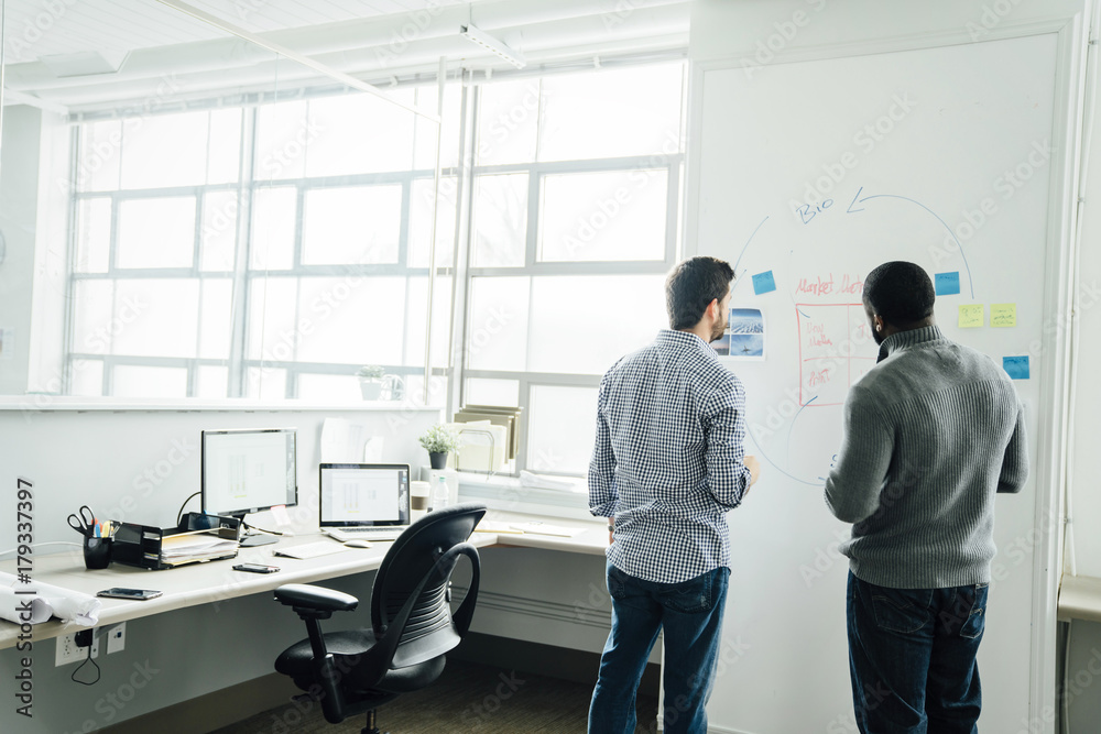 Businessmen using whiteboard in office Businessmen using whiteboard in office
