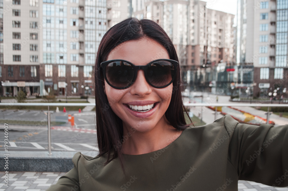 Selfie for you! Beautiful young woman in sunglasses making selfie while standing outdoors.