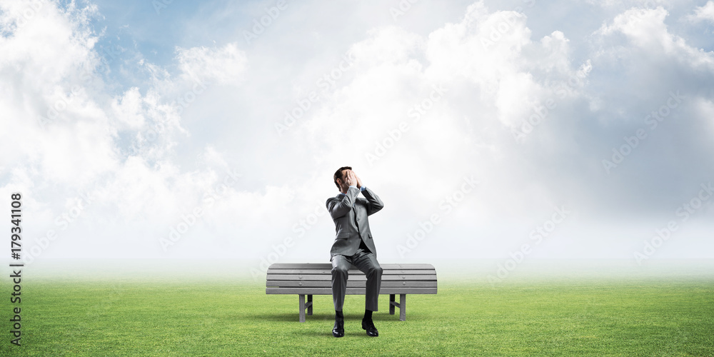 Young man in summer park on bench do not want to see anything