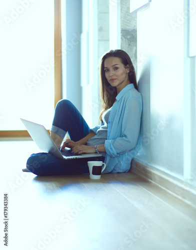 Young beautiful woman at home sitting on the floor with laptop. Young beautiful woman.