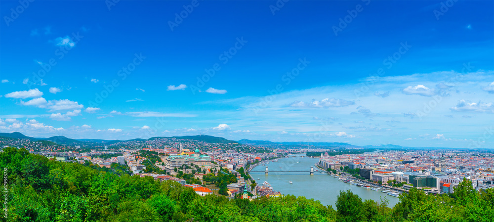 Panoramic cityscape view of hungarian capital city of Budapest from the Gellert Hill. The bridges connecting Buda and Pest across the river Danube. Summertime sunshine day, blue sky and green of trees