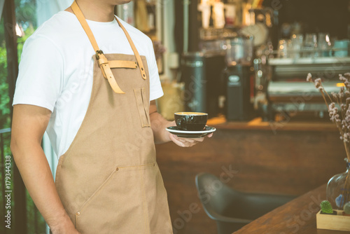 Waiter serving a cup of coffee in cafe,with vintage flter photo