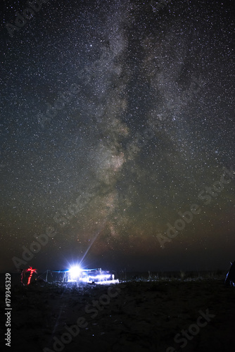 Illuminated tent on the beach against the background of a bright sky with milky way