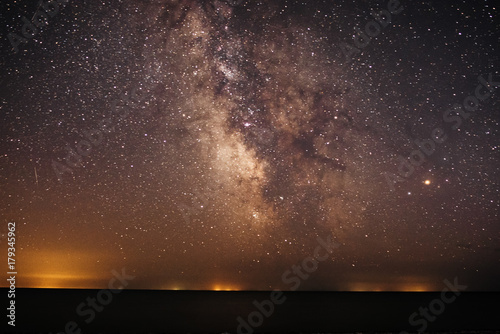 Obraz na płótnie Background of bright and night-starry sky with the Milky Way upon on it and light over the water w salonie
