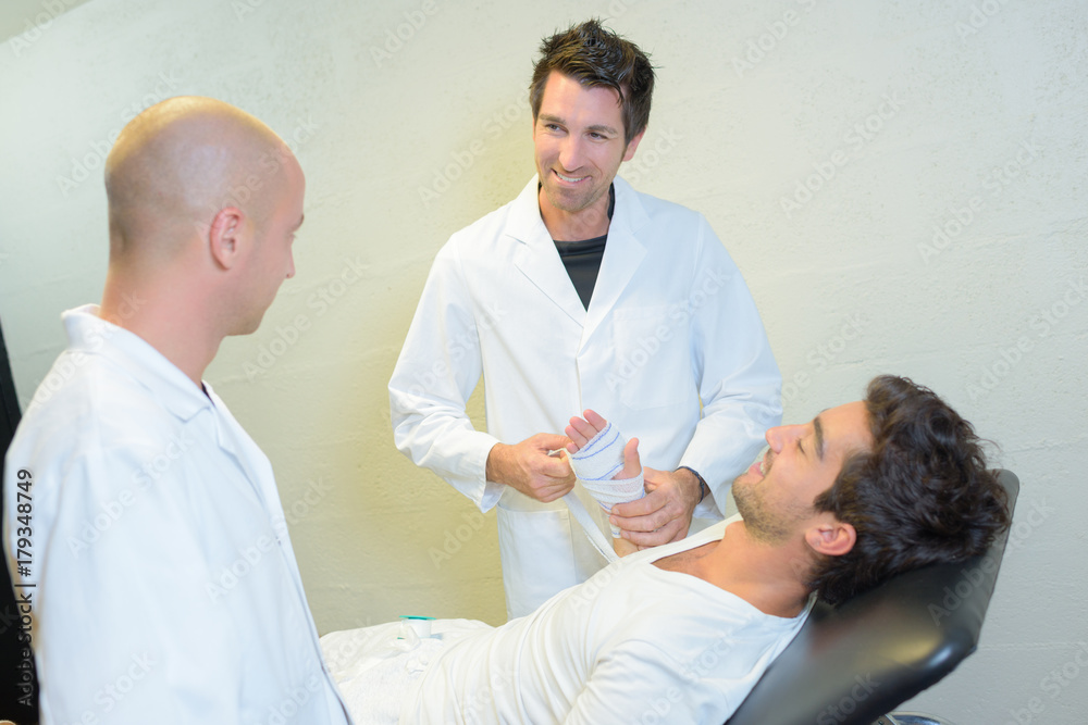 Obraz premium Patient having hand bandaged by doctor