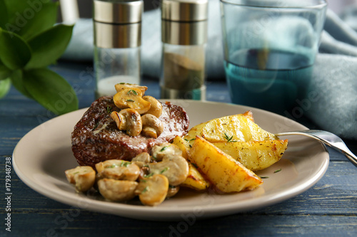 Plate with steak Diane and vegetable garnish on wooden table photo