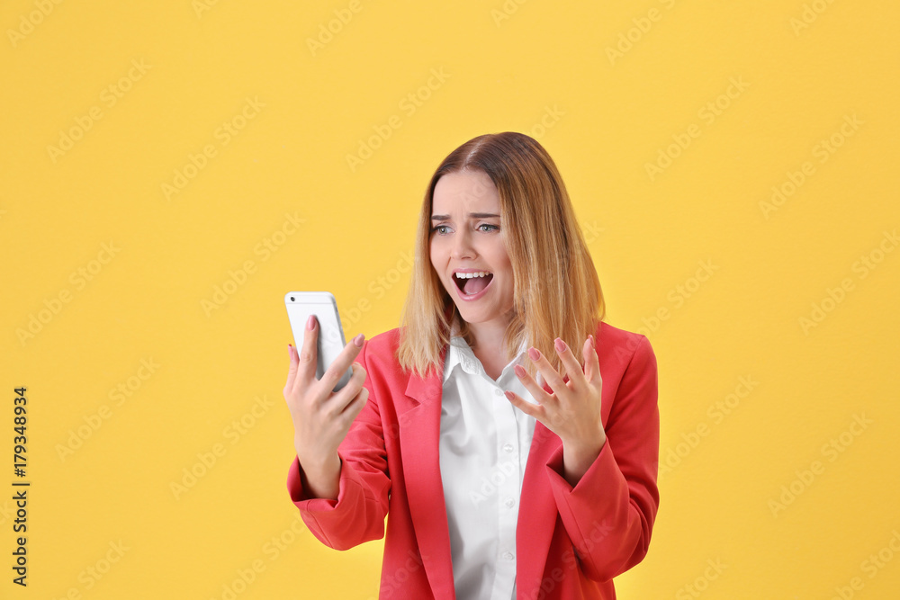 Naklejka premium Young woman using cell phone on yellow background
