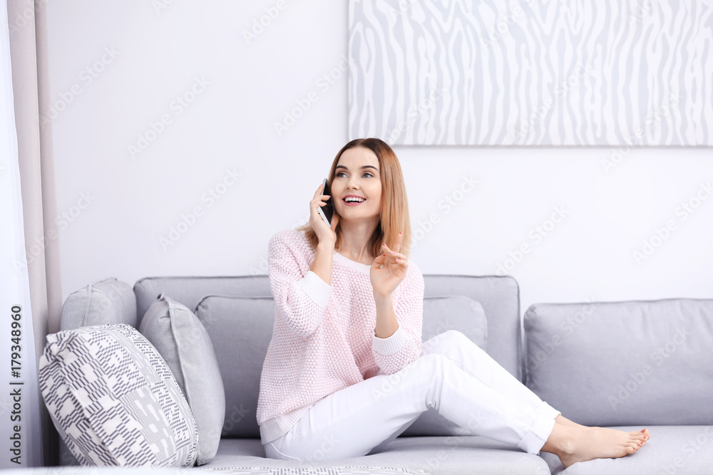 Young woman using cell phone while sitting on sofa at home Young woman using cell phone while sitting on sofa at home