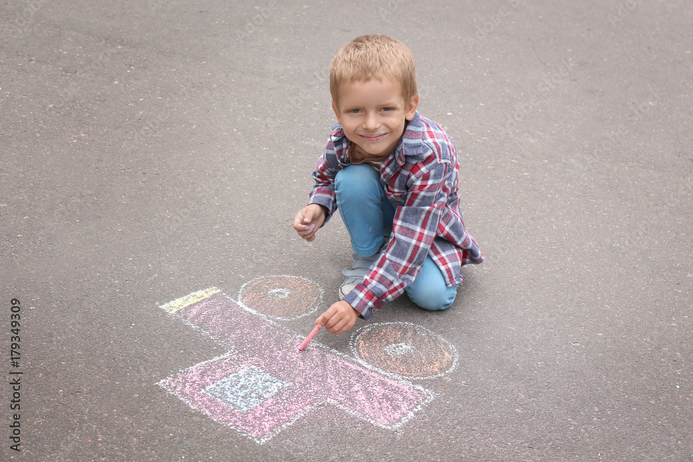 Naklejka premium Little boy drawing car with chalk on asphalt
