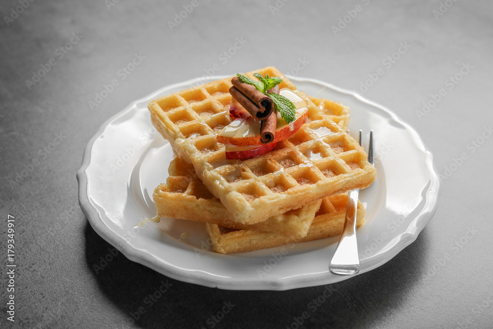 Plate with delicious cinnamon waffles on grey background Plate with delicious cinnamon waffles on grey background