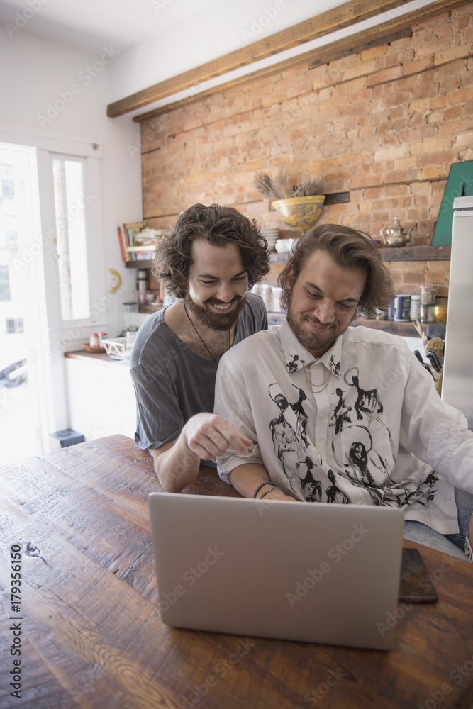 Gay couple using a laptop together Gay couple using a laptop together