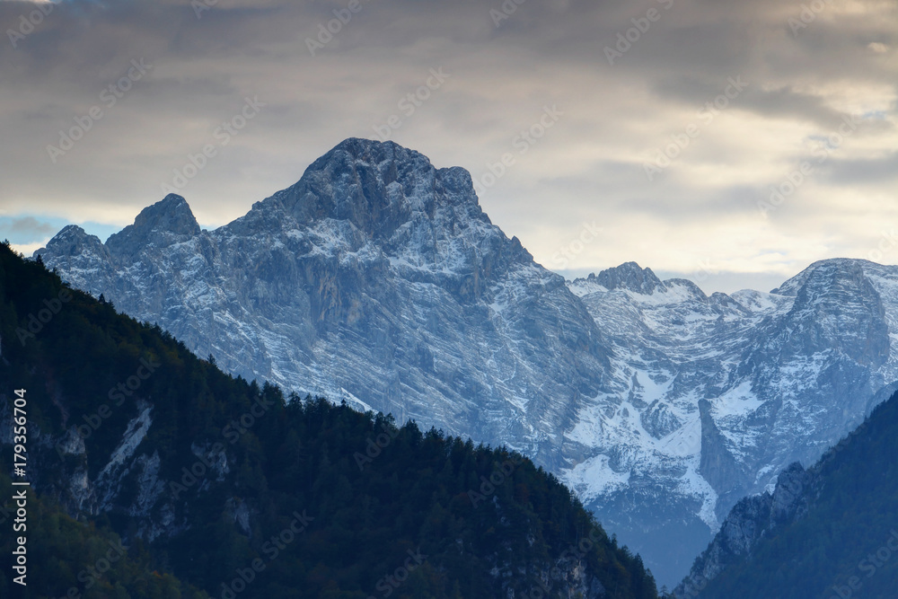 North face of snowy Rjavina peak towering above pine forests and ridges of Kot Valley at dusk, Triglav mountain group, Triglav National Park, Julian Alps, Slovenia, Europe
