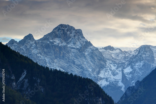 North face of snowy Rjavina peak towering above pine forests and ridges of Kot Valley at dusk, Triglav mountain group, Triglav National Park, Julian Alps, Slovenia, Europe
