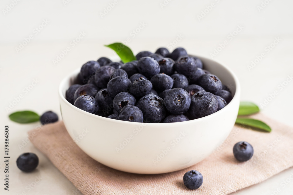 Juicy and fresh blueberries with green leaves on white bowl. Healthy eating Juicy and fresh blueberries with green leaves on white bowl. Healthy eating