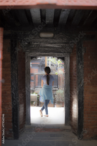girl standing outside the door of an ancient building © Puskar