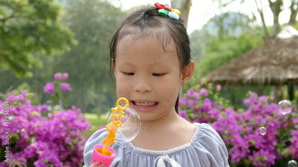 Little asian girl blowing bubbles in park ,slow motion.
Little asian girl blowing bubbles in park ,slow motion.