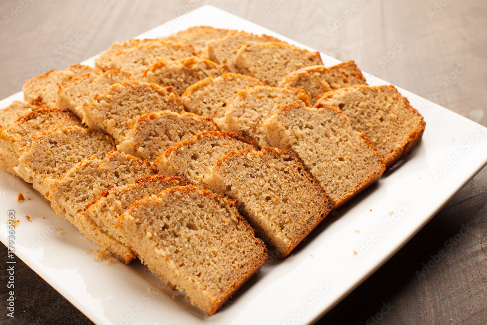 
Freshly baked pumpkin bread slices on white platter on dark wood background horizontal shot
