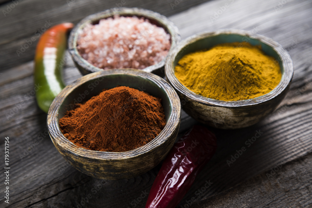 Various colorful spices on a wooden table in bowls Various colorful spices on a wooden table in bowls