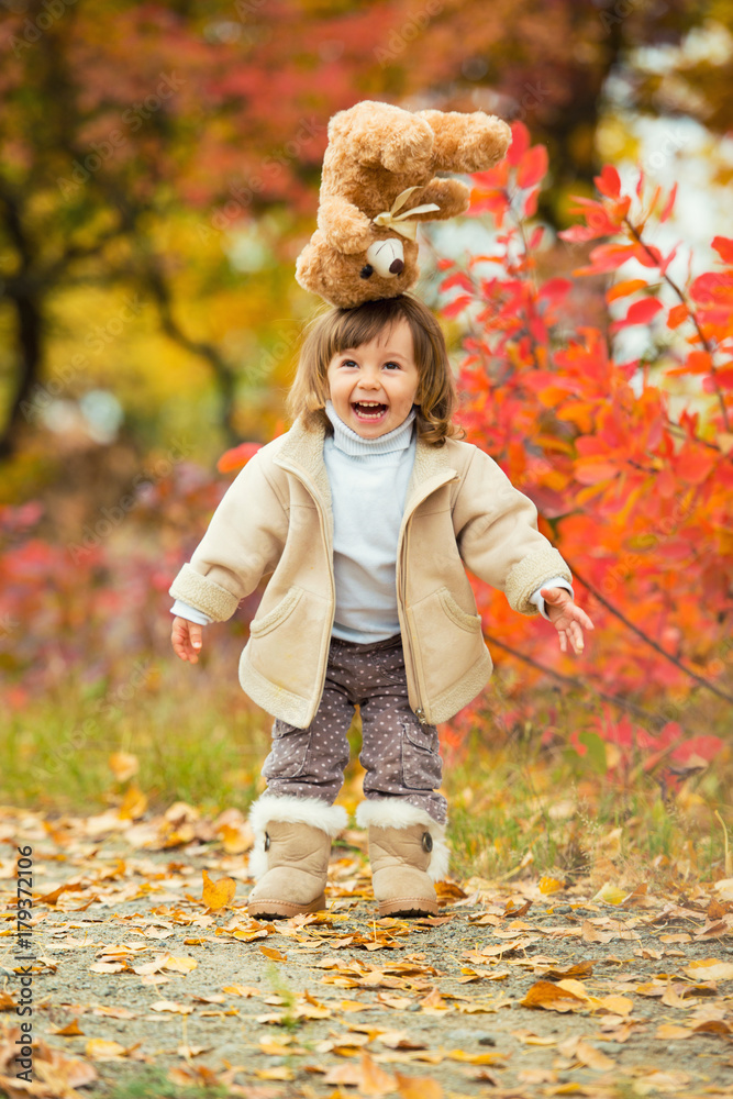 Little girl with a teddy bear in her hand on a background of autumn foliage. Autumn time. Little girl with a teddy bear in her hand on a background of autumn foliage. Autumn time.